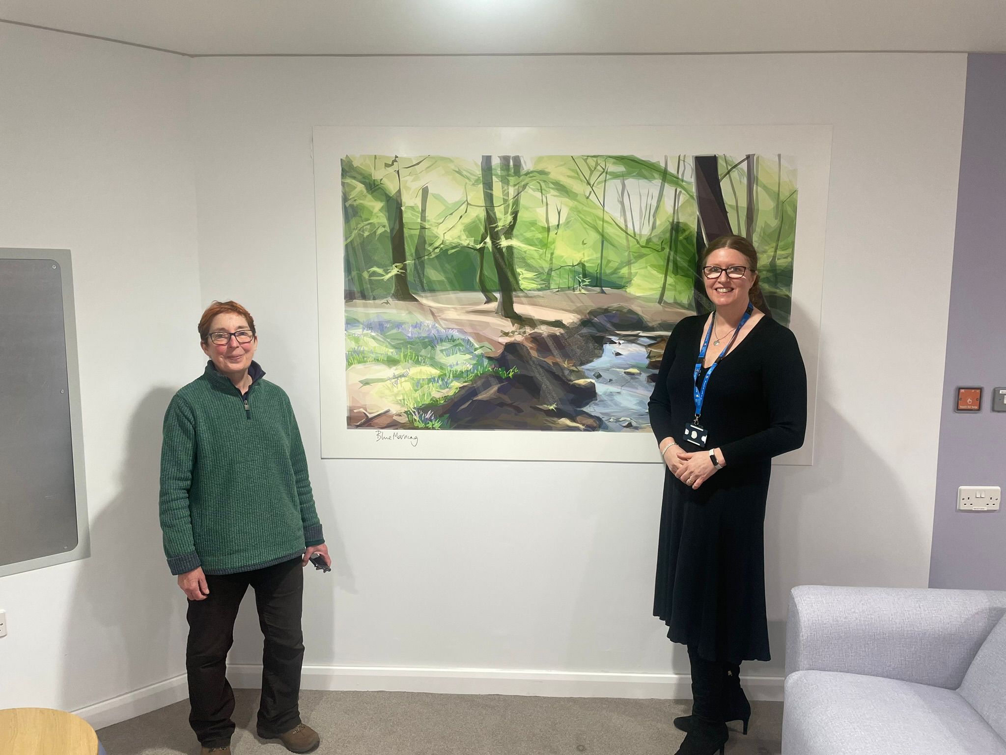 Artist, Jill Ray, and Sharon Mays, chair, stand in front of a work of art on a wall