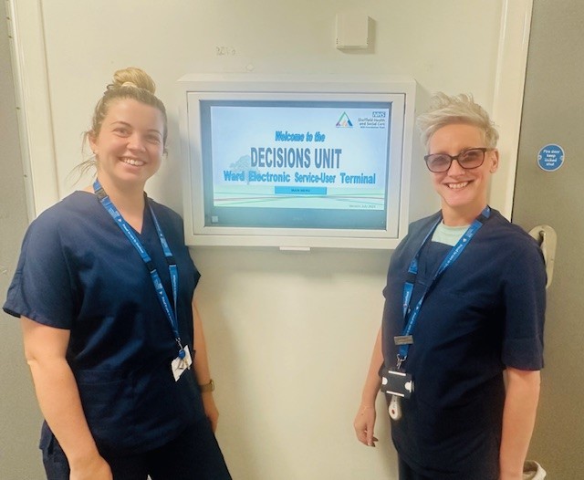 Decisions Unit staff smiling in front of sign