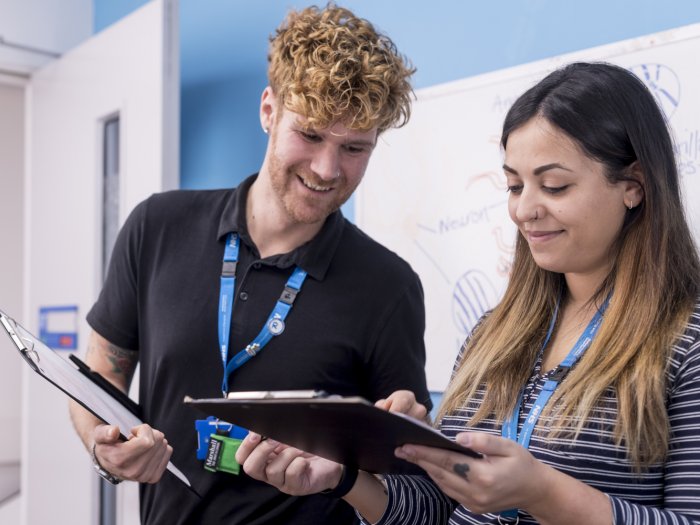 Man and woman, smiling, looking at clipboards