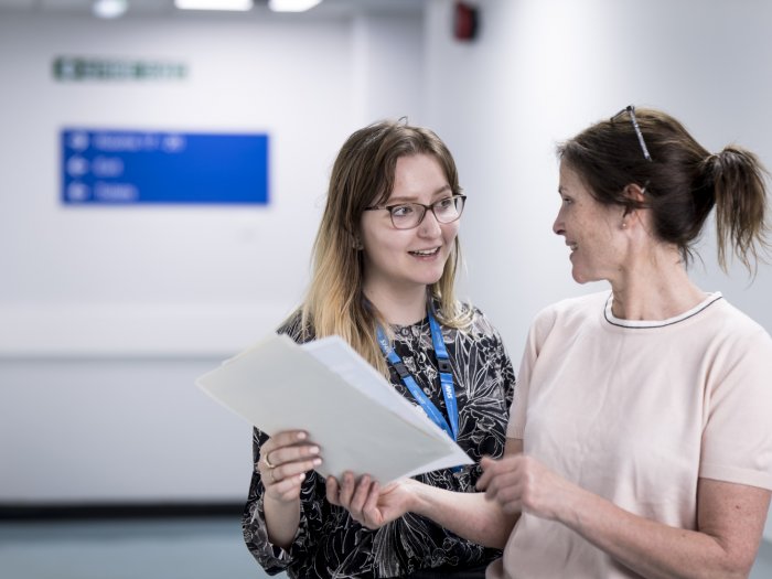 Woman standing with a woman, looking at each other, in a hospital, ward, smiling