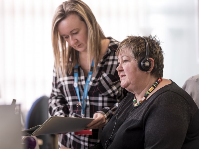 woman looking at notes with woman with headset