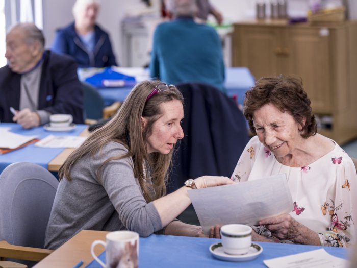 woman talking to an elderly woman at a table, patient