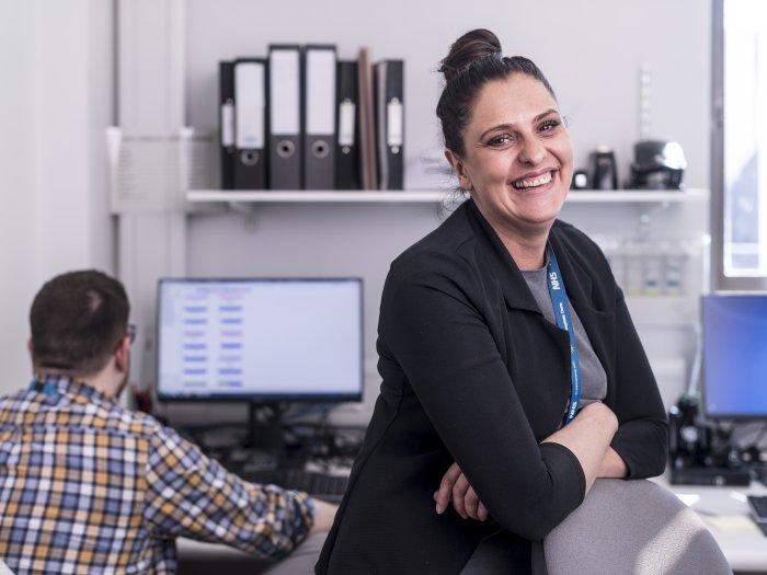 woman, in an office, smiling broadly, looking at the camera