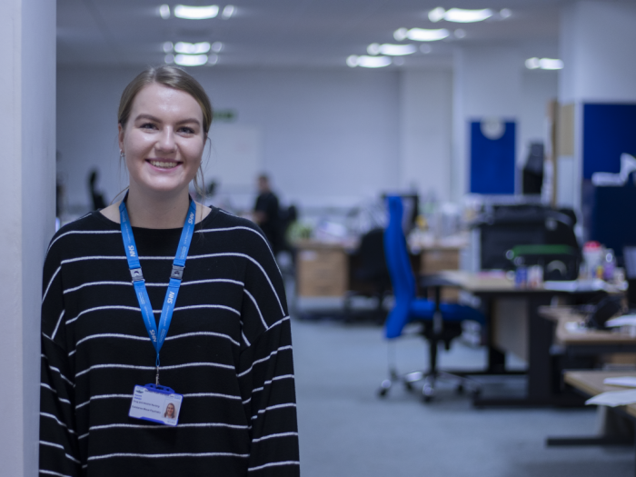 Woman in office, looking at camera, smiling