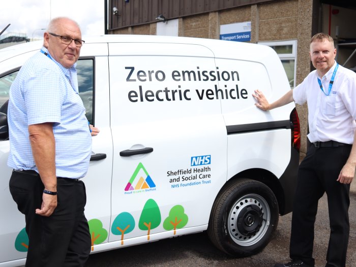 Two people stood in front of white van with livery showing it is an electric vehicle