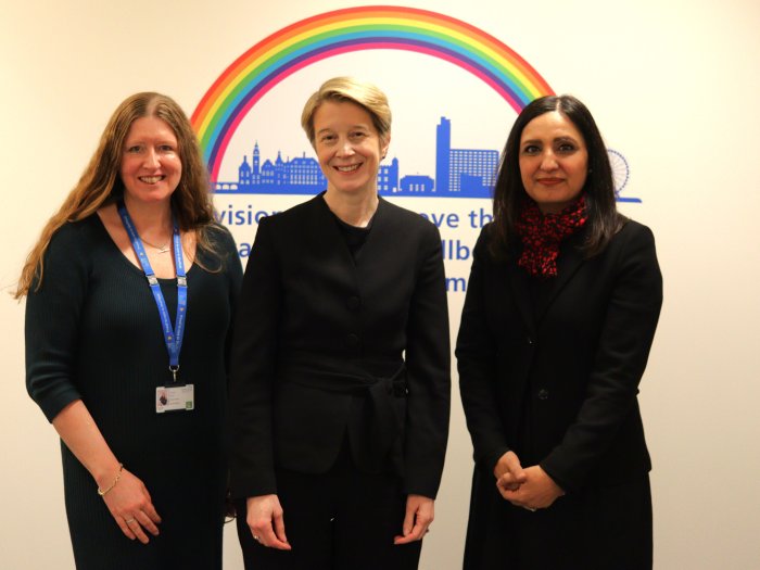 Sharon Mays, Amanda Pritchard, and Salma Yasmeen stand together wearing formal attire in front of a wall vinyl displaying Sheffield with a rainbow above it