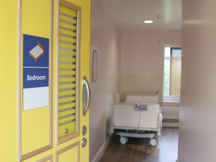 Bright yellow bedroom door open onto a medical but homely bedroom