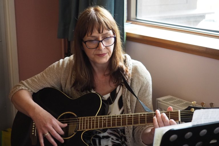 Women with glasses playing the guitar 