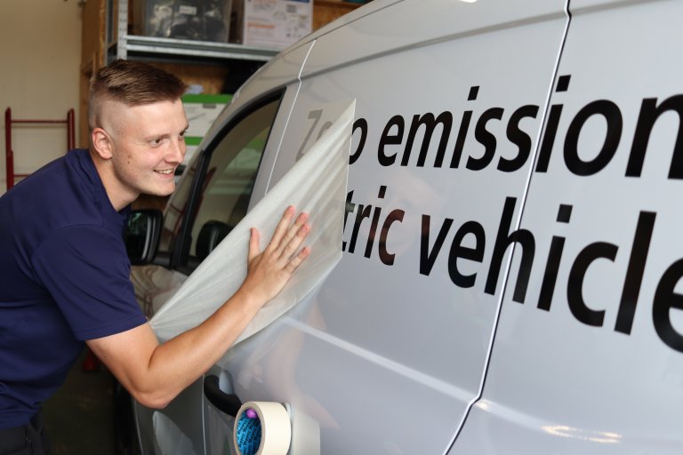 Person applying livery to white van