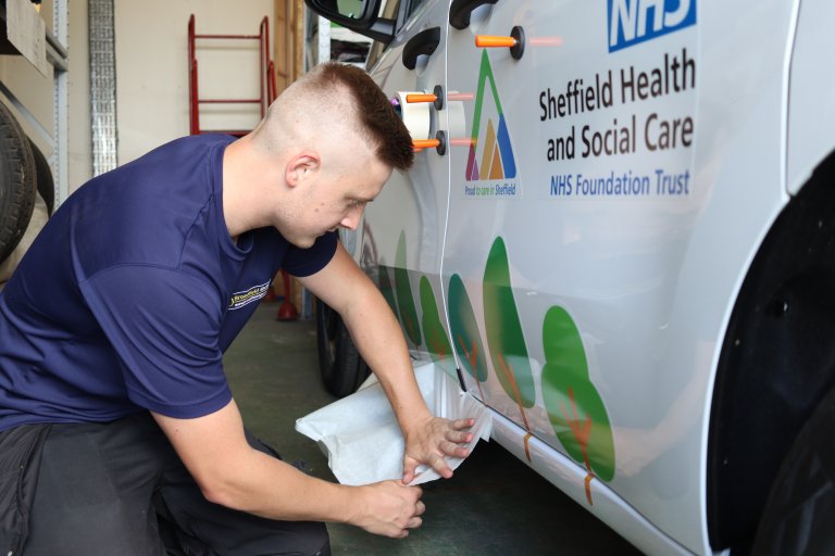 Man applying livery of tree graphics to white van