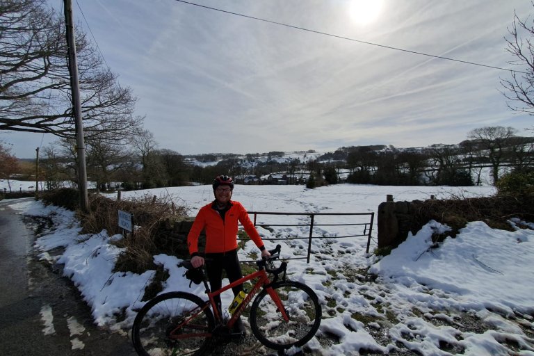 Person stood with a bike in front of a snowy landscape