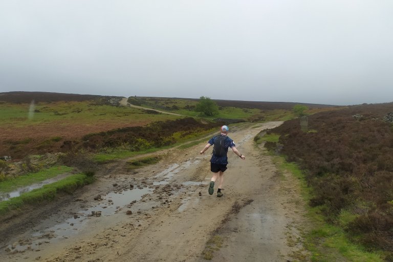 Person running on a rainy day in the Peak District along a brown rocky path