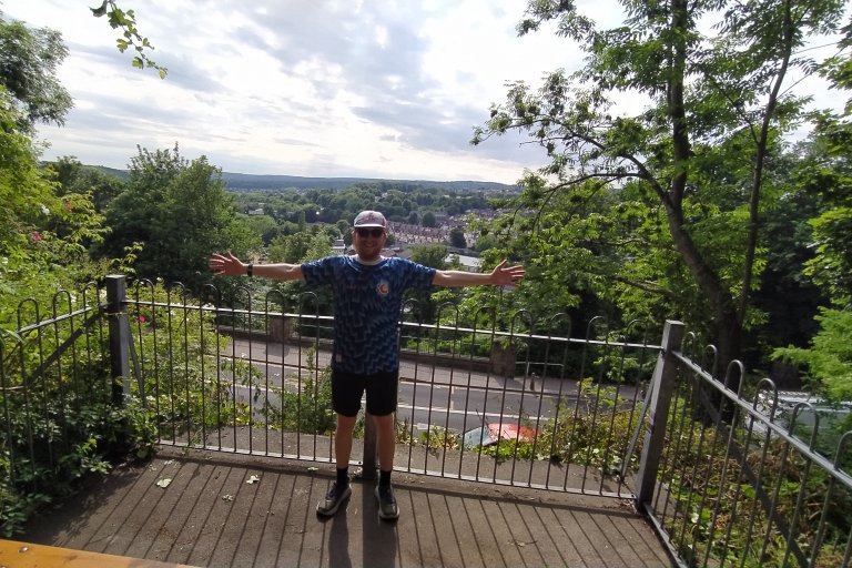 Person standing with arms outstretched on a balcony overlooking a view of Sheffield