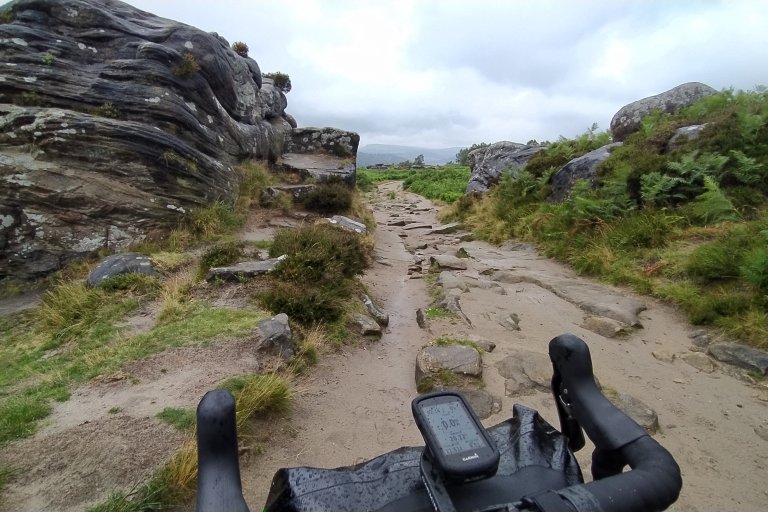 Bike handlebars can be seen on a rainy day along a rocky edge track in the Peak District