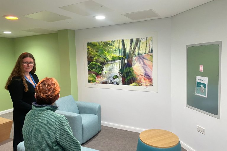 Jill Ray, artist, and Sharon Mays, chair, look at artwork on a wall