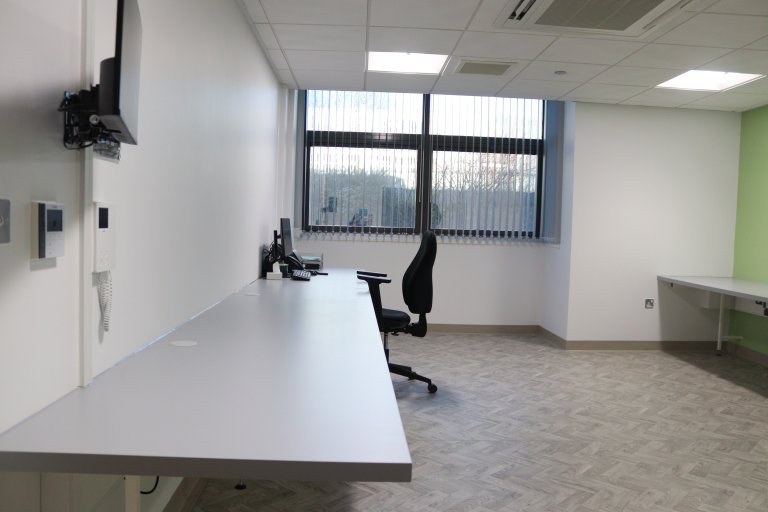 Office with two banks of desks and a chair at one end