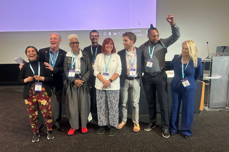 People on stage grouped together for a photo at a conference