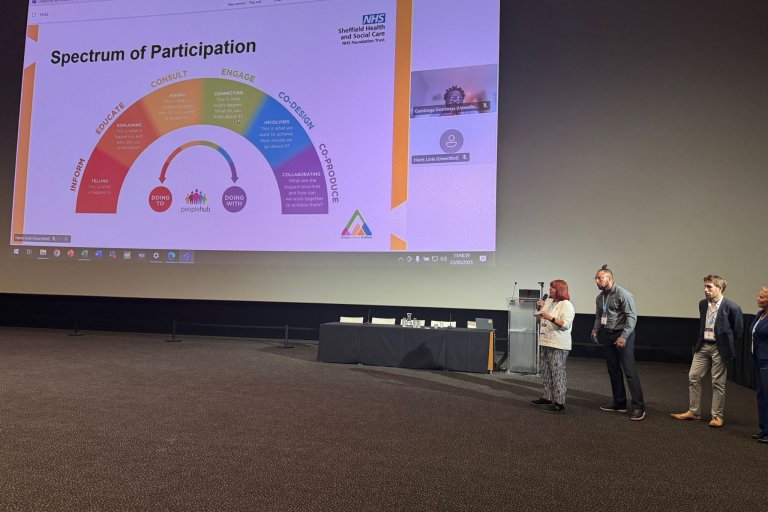 People presenting in front of a large screen at a conference